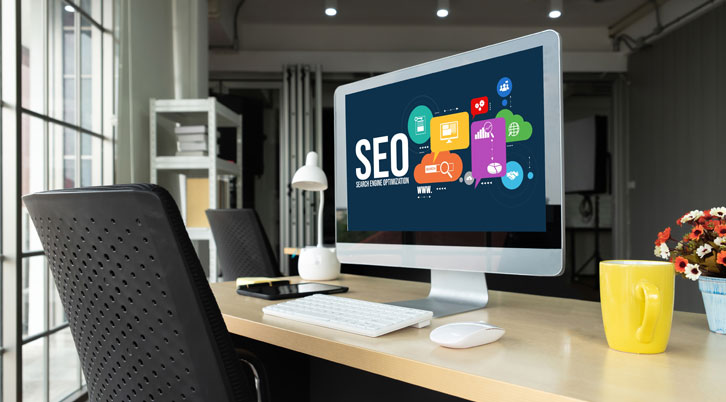 Office Desk With Computer Showing SEO On Screen.