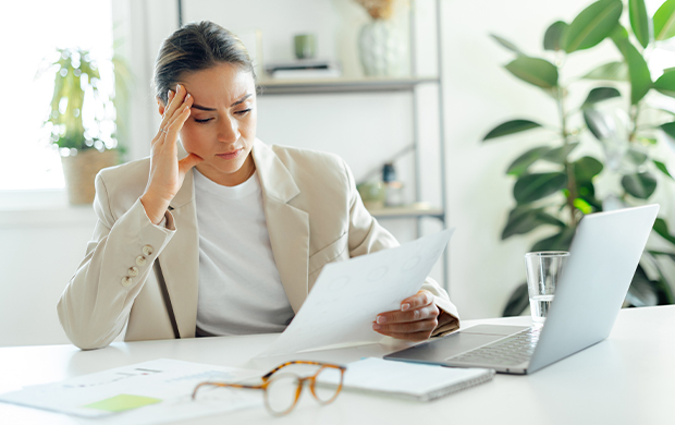 a woman seated at a desk, working on a laptop surrounded by papers a woman seated at a desk working on a laptop surrounded by papers